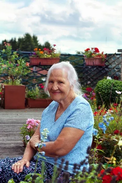 An older woman smiling in a garden full of flowers